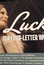 A woman standing next to a sign that says " luck is a four-letter word ".